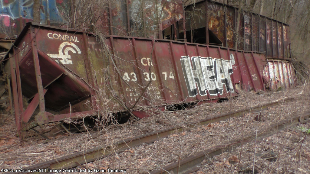 An old Conrail hopper lies along the hillside